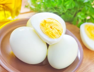 Hard-boiled eggs peeled and sliced on a ceramic plate with fresh parsley garnish.