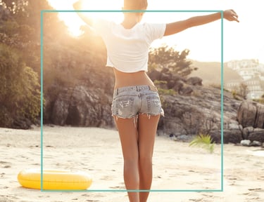 a woman standing on a beach with her arms up and arms outstretched out