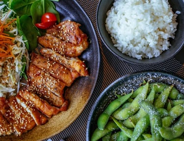 Grilled chicken teriyaki with sesame seeds served with white rice, edamame, and a fresh garden salad.