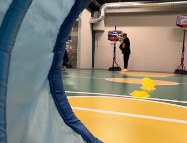 Vista attraverso un tunnel morbido in un'area multisport della palestra Move 2 Grow a Milano, con un adulto che aiuta un bamb