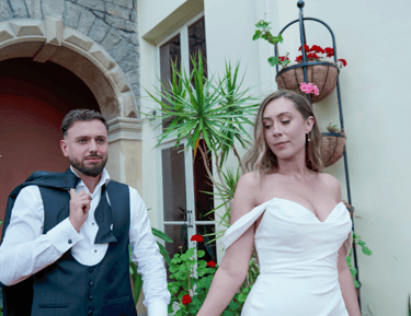 A bride and groom joyfully walking surrounded by floral decorations and smiling guests.