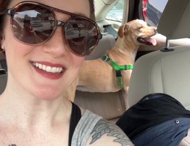 a woman with tattoos on her arm and a dog in the car