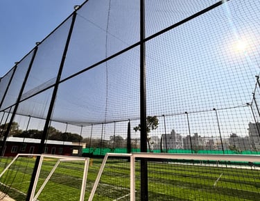 Wide shot of a sports ground fully enclosed with safety nets on a sunny day.