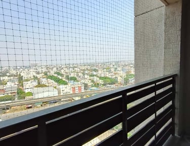 Wide view of a modern apartment balcony fitted with a white safety net by Arjilli Enterprises.