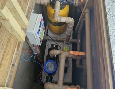 Sistema de filtragem de piscina com filtro de areia amarela, bomba e encanamento de PVC em caixa de