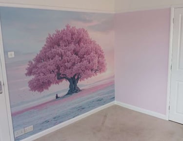 One wall with a mural depicting a cherry blossom tree, surrounded by a sky, sunset and pink field.
