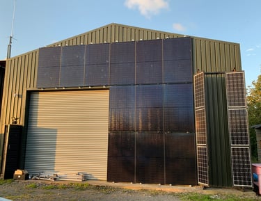 a building with vertical solar panels mounted in black on agricultural building