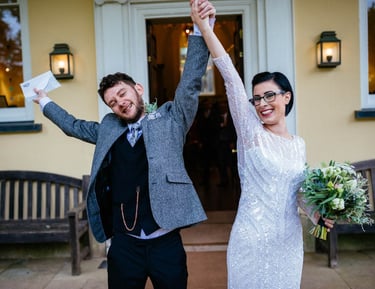 Just married joy at Aberglasney, bride and groom raising their hands in celebration outside the historic Welsh venue.