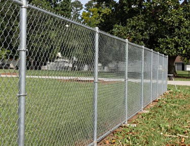 Durable galvanized steel chain link fence installed around a green lawn and garden area.