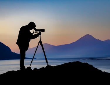 a man standing on a rock with a camera and a tripod