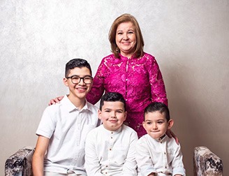 proud mother wearing pink standing behind her three boys wearing white