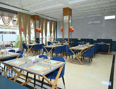 Modern restaurant dining room with blue chairs, wooden tables, and elegant interior decor.