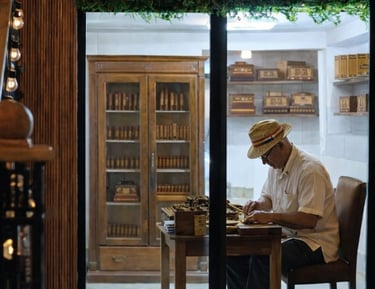 Professional cigar roller in a straw hat crafting authentic Cuban cigars in a luxury shop.