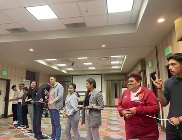 Diverse group of participants engaging in a team-building workshop activity with a white rope.