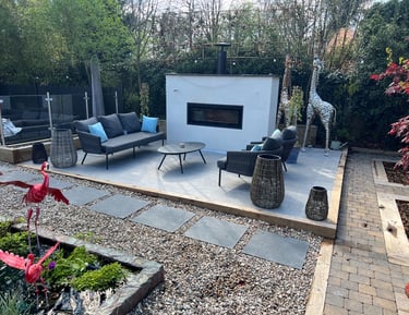 An outdoor living area with grey sofas and a fireplace built into a white rendered wall.