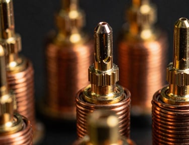 Extreme macro close-up of hand-wound copper coils and heavy-duty brass antenna terminals, dramatic amber studio lighting, high-contrast hardware details, 35mm film
