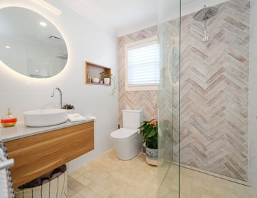 Modern private bathroom at Marche Home Stay with a floating vanity, mirror, rainfall shower, and warm natural finishes.