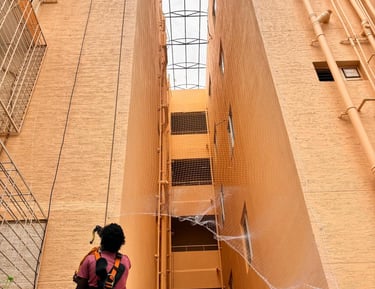 Installation team fitting safety nets around duct areas on an apartment exterior.
