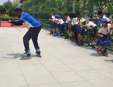A group of school students in uniform with helmets learning inline skating from an instructor on an outdoor rink.