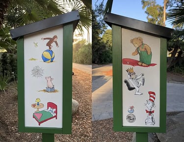Hand-painted Little Free Library featuring Curious George, Corduroy, and the Cat in the Hat.