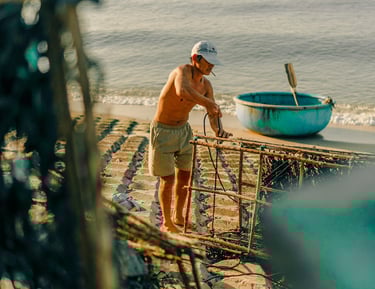 a man standing on a beach with a boat in the background