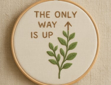 Embroidery hoop on a neutral background featuring the motivational phrase ‘The Only Way Is Up’