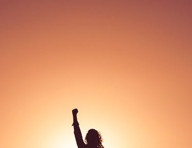 A confident woman with hand raised to sky