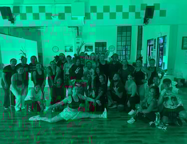 A group of dancers posing in front of a mirror with smiling faces.