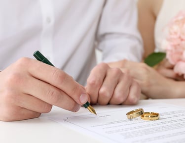 a man and woman holding wedding rings and signing license