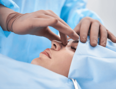 Surgeon performing a rhinoplasty procedure on a female patient in a medical clinic.