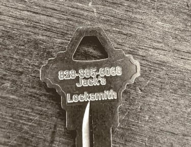 Metal key engraved with "Jack's Locksmith" and phone number, representing professional locksmith services.