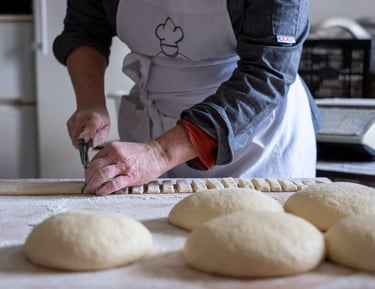 Une boulangère artisanale qui coupe sa pâte à pain