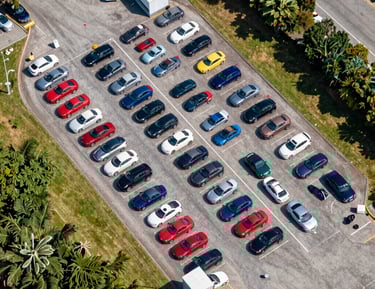 A close-up of hands exchanging car keys with a blurred vehicle in the background.