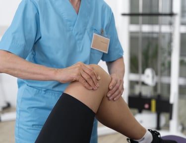 Ein Arzt bzw. Orthopäde untersucht das Knie eines Patienten/einer Patientin.