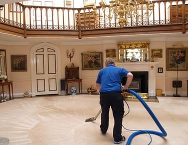 Professional cleaner using steam equipment for deep carpet cleaning in a luxury home interior.