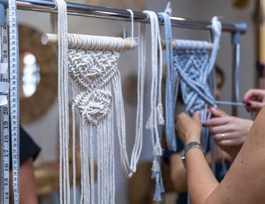 Manos artesanas elaborando un tapiz decorativo de macramé hecho a mano en un perchero,