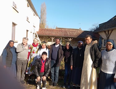 A diverse group of Catholic nuns and priests standing together in a sunny courtyard for a community photo.