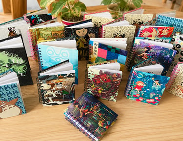 Colección de cuadernos de espiral con diseños de anime de Studio Ghibli y One Piece sobre una mesa d
