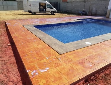 Hormigón impreso en color naranja alrededor de piscina, resistente y decorativo para exteriores modernos.