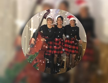 trois femmes en robe rouge et noire à carreaux et des bonnets de père Noël avec une guitare et une c