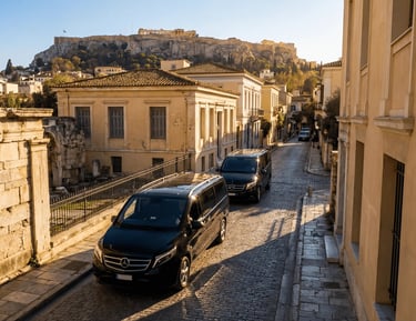 Two black Mercedes-Benz Vito minivans for private tours driving through historic Plaka district with the Acropolis in Athens
