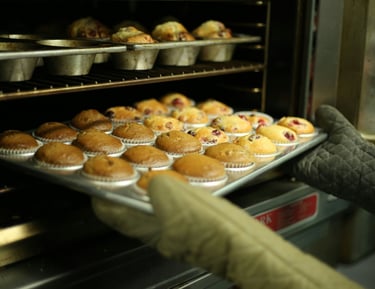 Muffins de arándano recién horneados siendo retirados de un horno 