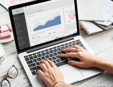 Person typing on a laptop keyboard analyzing a business chart with growth data analytics on the screen.