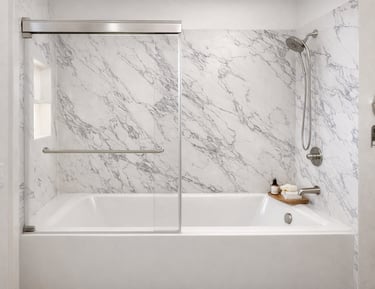Modern bathroom featuring a white bathtub with marble wall panels and sliding glass doors.