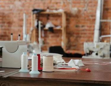 Tres carretes de hilo blando en una mesa de trabajo café y fondo de tabiques rojos