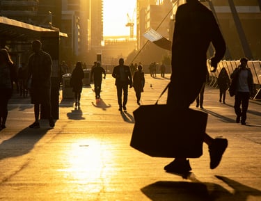 An important man with a suitcase walking along a busy sidewalk at sunset