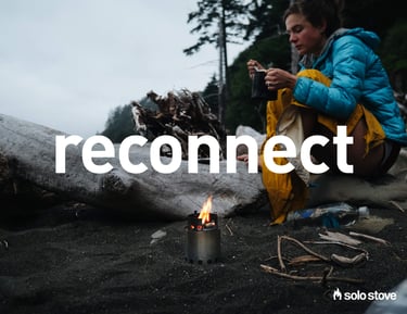 Woman sitting on the beach with small Solo Stove 