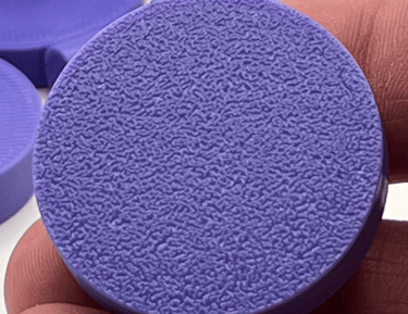Close-up of a purple 3D printed frag plate showing a textured fuzzy skin surface finish.