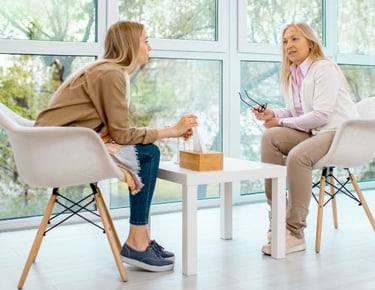 two women sitting at a table with a cup of coffee