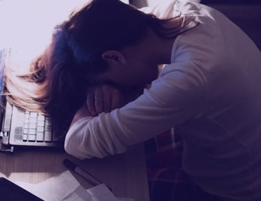 pessoa cansada por nao dormir bem e esta com a cabeça apoida sobre a escrivaninha